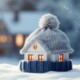 Ein Hausmodell im Schnee mit Schal und Mütze
