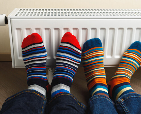 legs with colorful socks in front of heating radiator; Neues GEG