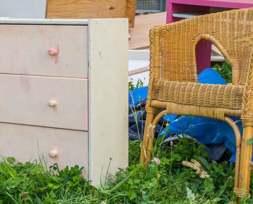 Alte Möbel, eine Kommode, ein Stuhl und anderes, stehen auf der Wiese vor dem Haus | Geerbte Immobilie entrümpeln