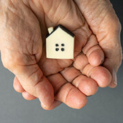 Inheritance concept. Elderly woman hands holds a little toy house. Inherited property idea; Erbschaftssteuer