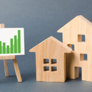 Holzhäuser und eine Lerntafel mit Statistiken als Symbol für die Immobilienwertermittlung