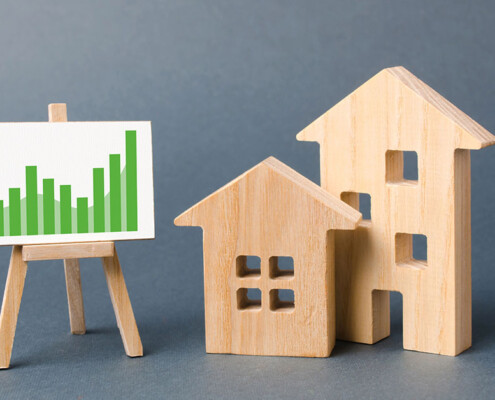 Holzhäuser und eine Lerntafel mit Statistiken als Symbol für die Immobilienwertermittlung