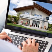 Ein Mann sitzt zuhause auf seinem Sofa am Laptop und lässt den Wert seiner Immobilie mit einem Online-Tool einschätzen | Immobilienbewertung