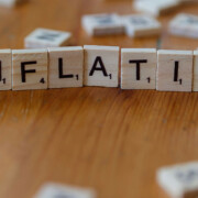 Auf einem Tisch liegt aus Scrabble-Buchstaben gelegt das Wort "Inflation" als Symbol für Immobilieninvestments während einer Inflation | Immobilieninvestment
