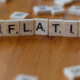Auf einem Tisch liegt aus Scrabble-Buchstaben gelegt das Wort "Inflation" als Symbol für Immobilieninvestments während einer Inflation | Immobilieninvestment