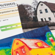 Ein Energieausweis liegt neben zwei Bildern von Häusern. Das eine ist ein realistisches Foto, das andere stellt das Gebäude als Wärmebild dar.