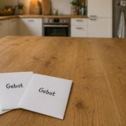 Drei Umschläge mit der Aufschrift ‚Gebot‘ auf einem Holztisch in moderner Küche, symbolisieren das Bieterverfahren beim Immobilienkauf. | Bieterverfahren