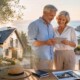 Älteres Ehepaar plant den Lebensabend im Ausland und informiert sich mit Immobilienunterlagen über ein neues Zuhause in sonniger Lage am Meer. I Lebensabend im Ausland
